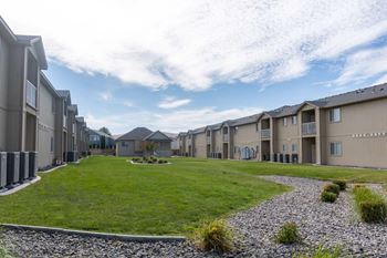 Courtyard with large grass area, well-maintained landscaping, and blue skies. at Pine Tree Park, Kennewick, 99337
